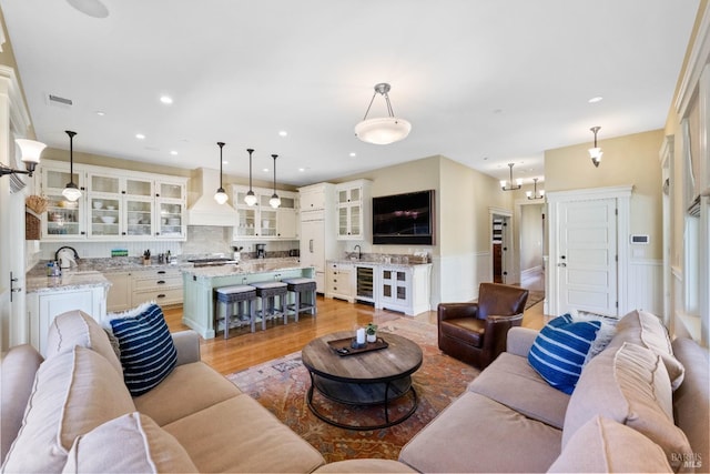 living room with recessed lighting, a wainscoted wall, light wood-style flooring, and wine cooler