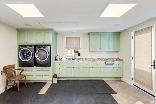 clothes washing area featuring a sink, washing machine and dryer, and cabinet space