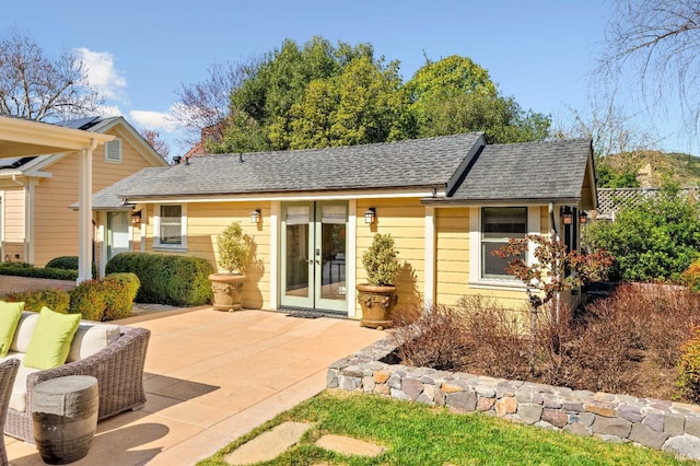 back of property with french doors, a shingled roof, and a patio area