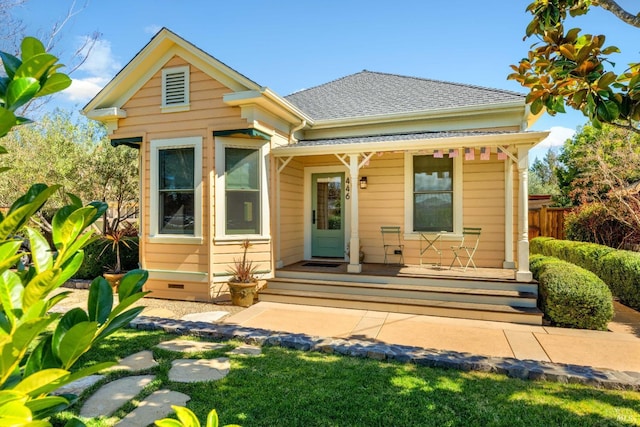 bungalow-style home featuring a porch, a shingled roof, and fence