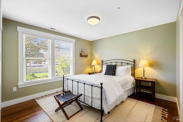 bedroom with baseboards, light wood finished floors, visible vents, and multiple windows