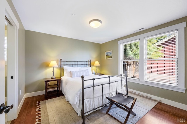 bedroom featuring baseboards, wood finished floors, and visible vents