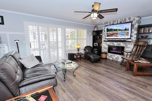 living room with ceiling fan, ornamental molding, a fireplace, and wood finished floors