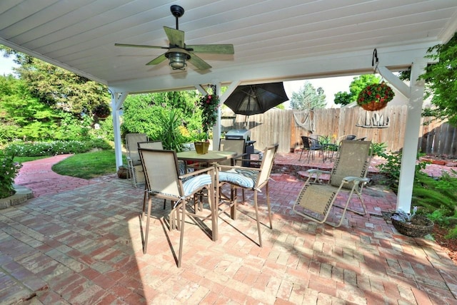 view of patio / terrace with area for grilling, fence, a ceiling fan, and outdoor dining space