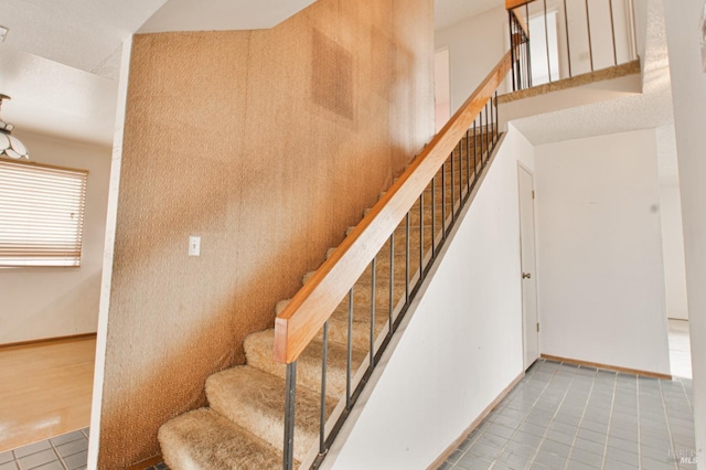 stairway with tile patterned floors and baseboards