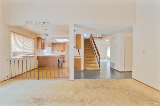 kitchen with carpet floors, tile patterned floors, baseboards, and brown cabinets
