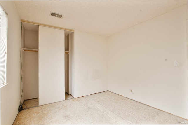 unfurnished bedroom with light colored carpet and a closet