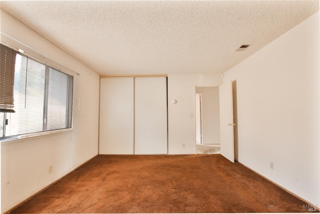unfurnished bedroom featuring light carpet, a textured ceiling, and a closet
