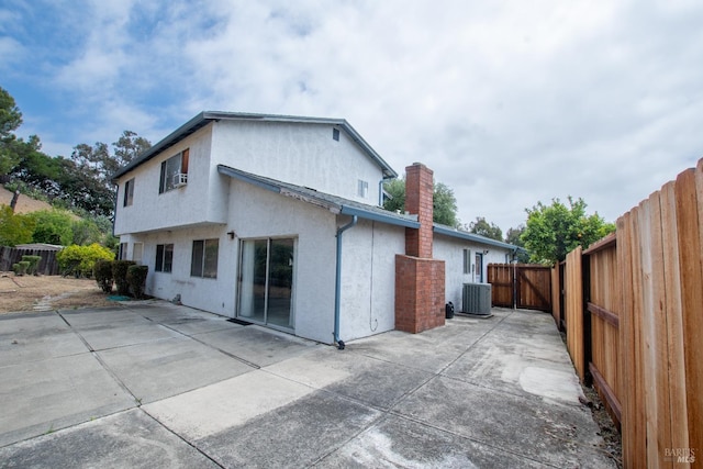 rear view of house with a patio area, stucco siding, a fenced backyard, central air condition unit, and a chimney
