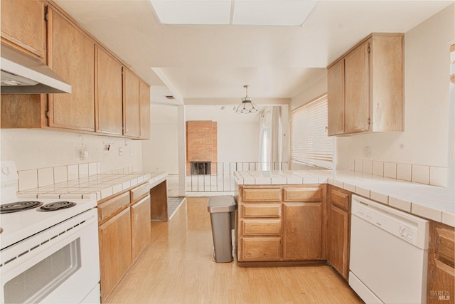 kitchen with white appliances, light wood-type flooring, a peninsula, and a chandelier