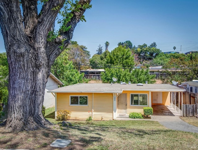 view of front of home featuring a front lawn, fence, an attached carport, and concrete driveway