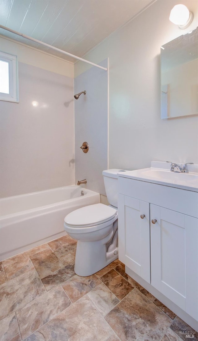 full bathroom with washtub / shower combination, vanity, toilet, and stone finish flooring