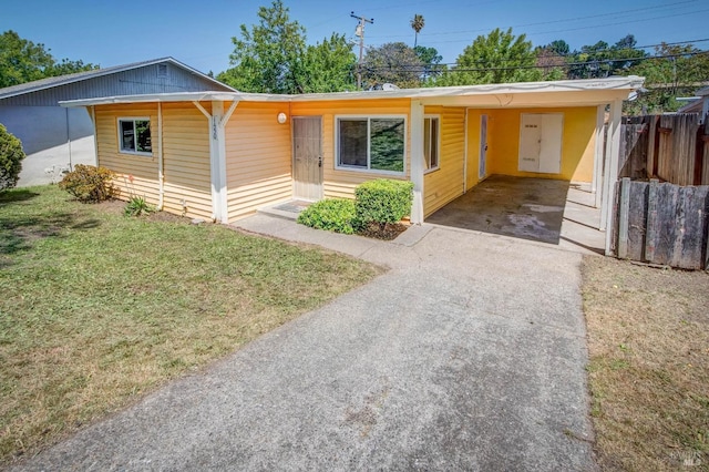 view of front facade featuring a front lawn, fence, an attached carport, and concrete driveway