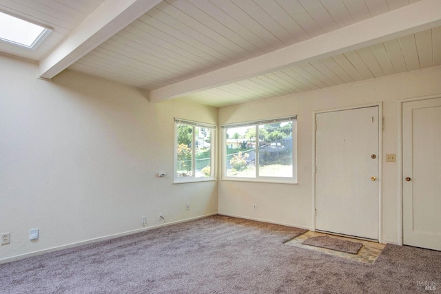 carpeted foyer with beamed ceiling, a skylight, and baseboards