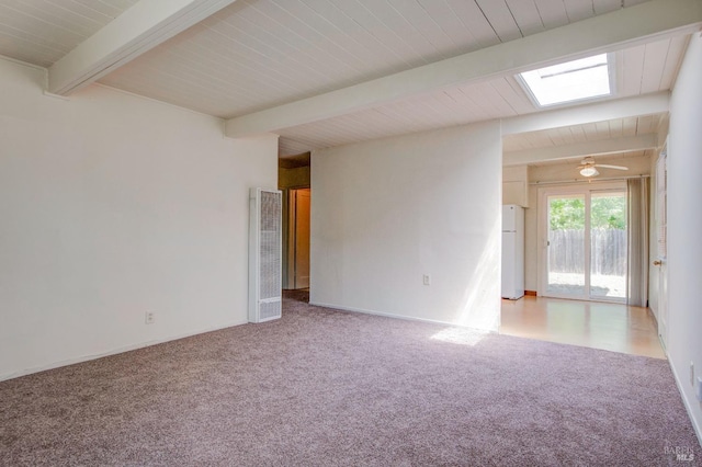 spare room with a skylight, light carpet, beam ceiling, and a heating unit