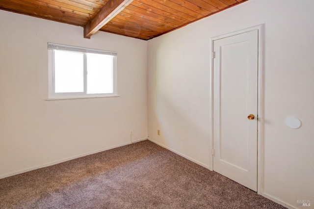 spare room featuring wooden ceiling, baseboards, carpet, and beam ceiling