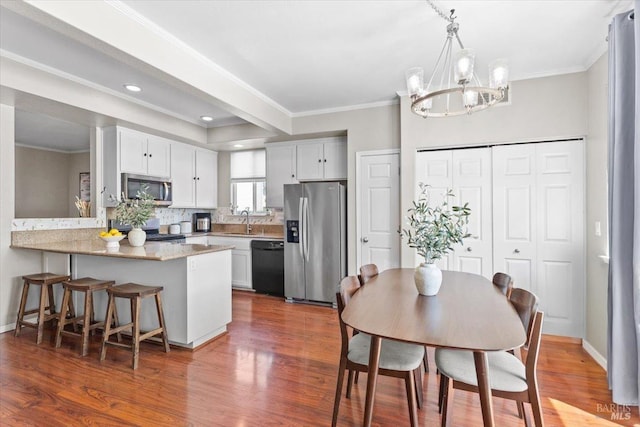 kitchen featuring a chandelier, appliances with stainless steel finishes, ornamental molding, and a sink