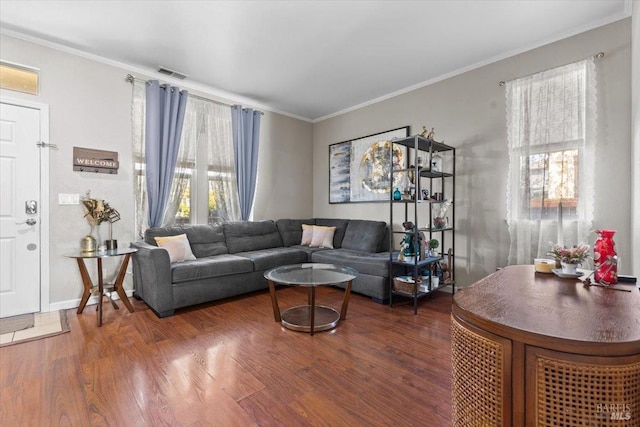 living area with visible vents, ornamental molding, and wood finished floors