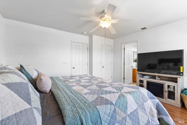 bedroom with light wood-style floors, a ceiling fan, and visible vents