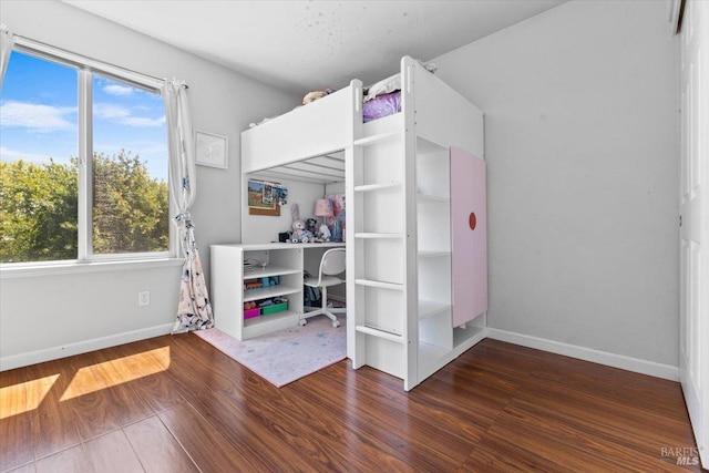 bedroom with baseboards, multiple windows, and wood finished floors