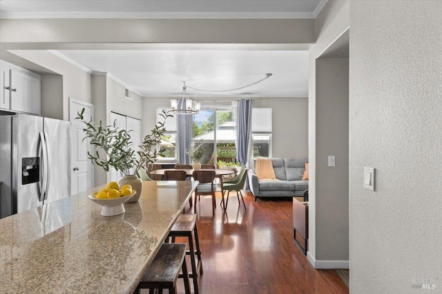 dining room with crown molding, baseboards, a notable chandelier, a textured wall, and dark wood-type flooring