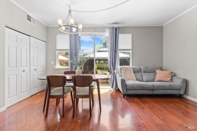 dining space with an inviting chandelier, wood finished floors, and visible vents