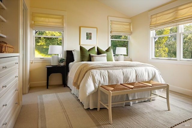 bedroom with baseboards, multiple windows, and lofted ceiling