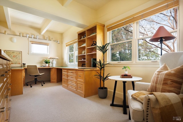 office area with light colored carpet, built in desk, and beamed ceiling