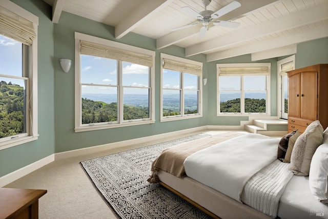 carpeted bedroom featuring baseboards, beamed ceiling, and a ceiling fan