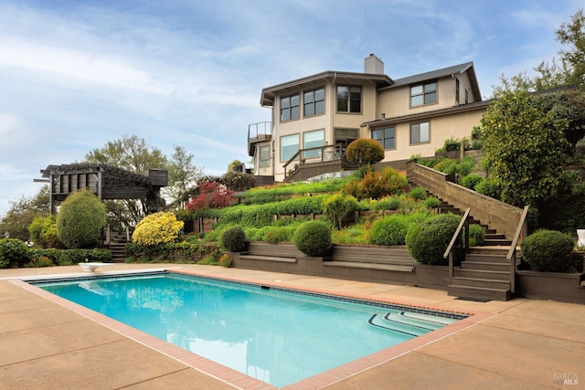 outdoor pool with a patio, a diving board, and stairway