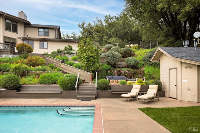 pool featuring a patio, fence, an outbuilding, and an outdoor hangout area