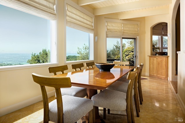 sunroom featuring arched walkways, beam ceiling, and a healthy amount of sunlight