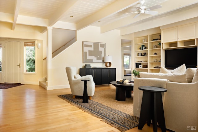 living room with light wood-style floors, baseboards, beamed ceiling, and a wealth of natural light