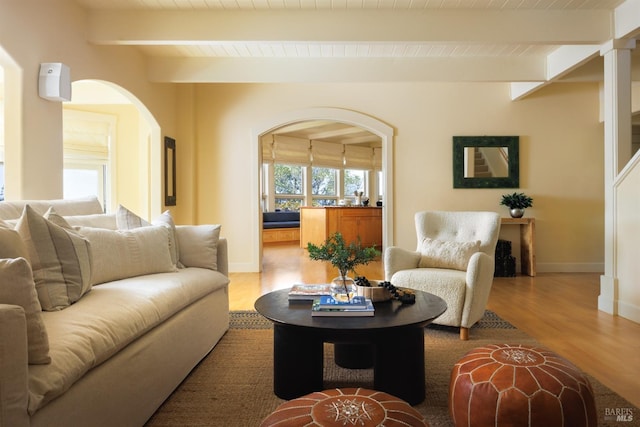 living area with arched walkways, wood finished floors, wooden ceiling, baseboards, and beamed ceiling