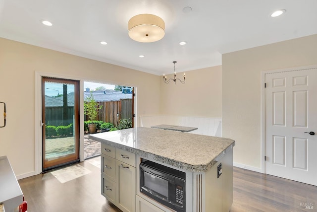 kitchen with a kitchen island, black microwave, wood finished floors, light countertops, and a chandelier