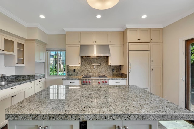 kitchen featuring exhaust hood, plenty of natural light, paneled fridge, and a center island