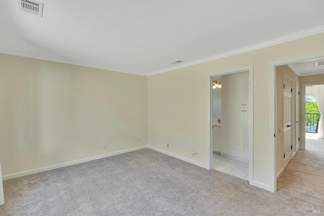 empty room with visible vents, baseboards, crown molding, and light colored carpet