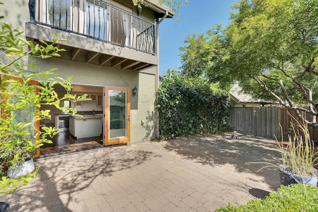 view of patio featuring fence and a balcony