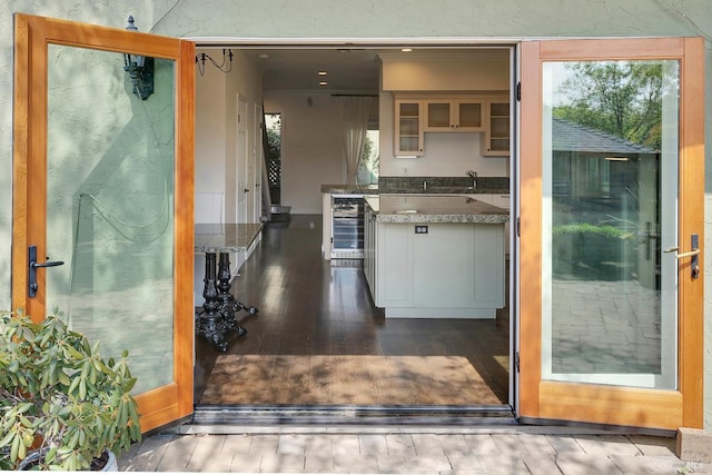 kitchen featuring glass insert cabinets, dark wood-style floors, beverage cooler, and a sink