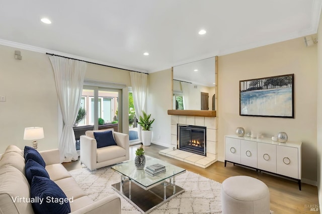 living area with ornamental molding, wood finished floors, baseboards, recessed lighting, and a tiled fireplace