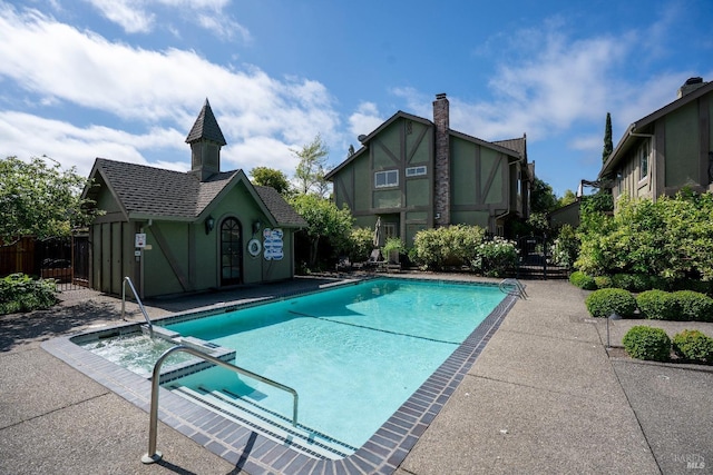 view of swimming pool featuring fence, a patio, and a pool with connected hot tub