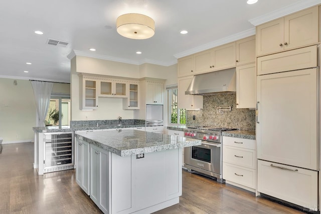kitchen with plenty of natural light, high quality appliances, visible vents, beverage cooler, and under cabinet range hood