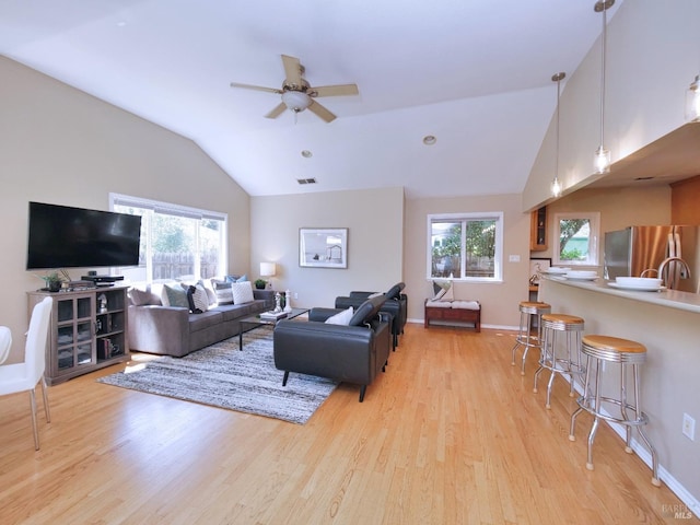 living area with lofted ceiling, light wood-style flooring, ceiling fan, and baseboards