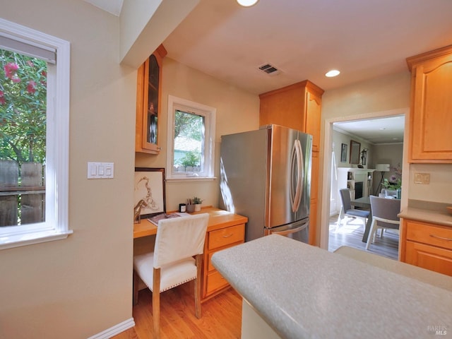 kitchen with freestanding refrigerator, light wood-style floors, glass insert cabinets, light countertops, and an office area