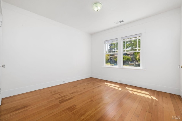 empty room featuring baseboards, light wood-style flooring, and visible vents