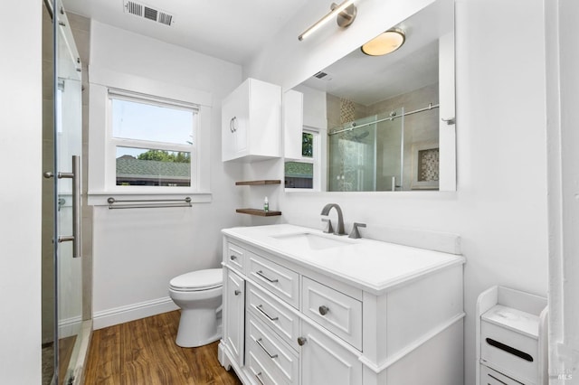 bathroom featuring vanity, toilet, a shower stall, wood finished floors, and visible vents