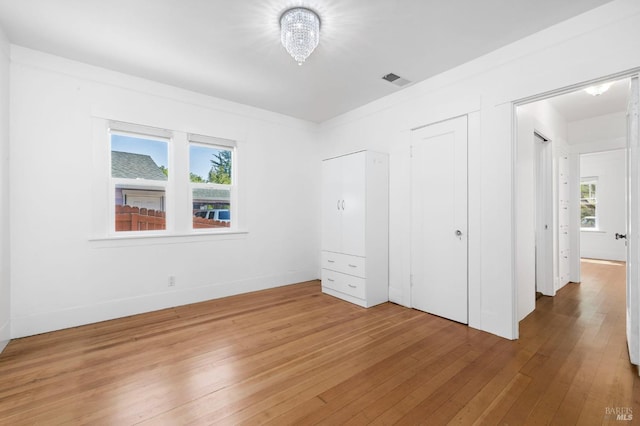 unfurnished bedroom featuring baseboards, visible vents, and light wood finished floors