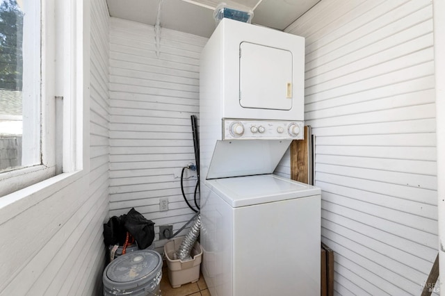 washroom with laundry area, wood walls, and stacked washer / dryer