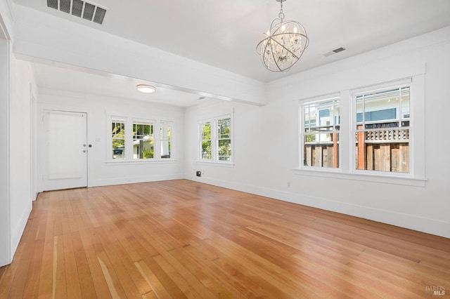 spare room featuring baseboards, visible vents, an inviting chandelier, and light wood finished floors