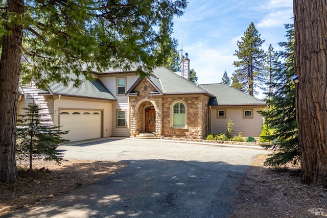 35600 Rock Creek Rd, Shingletown, CA 96088 - traditional home featuring driveway, a chimney, roof with shingles, an attached garage, and stone siding